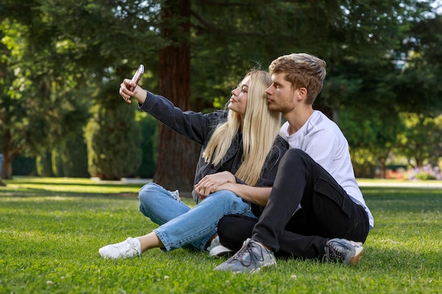 Młoda dziewczyna siedzi ze swoim chłopakiem i robi selfie