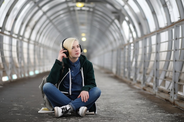 Młoda dziewczyna słucha muzyki w dużych słuchawkach w tunelu metra