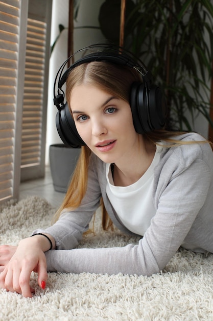 Młoda dziewczyna słucha relaksującej muzyki ze słuchawkami leżącymi na podłodze