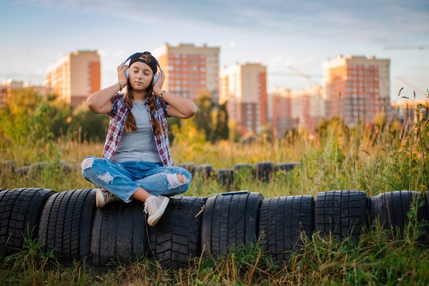 Młoda dziewczyna, słuchanie muzyki na słuchawkach, miejski styl uliczny, kobieta hipster zewnątrz styl ulicy