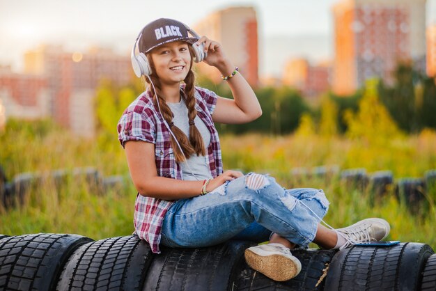 Młoda dziewczyna, słuchanie muzyki na słuchawkach, miejski styl uliczny, kobieta hipster zewnątrz styl ulicy