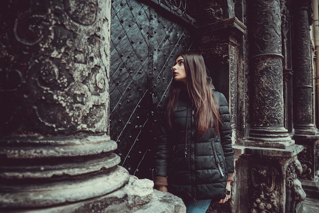 Młoda dziewczyna stoi na tle starego gotyckiego muru