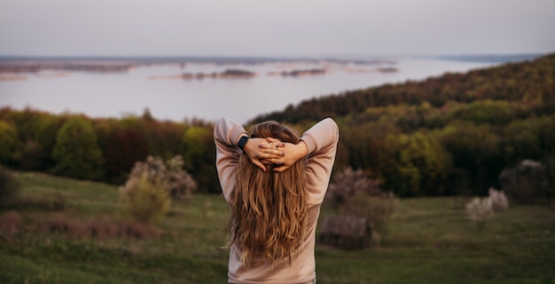 Zdjęcie młoda dziewczyna stoi plecami z blond włosami i rękami nad głową.