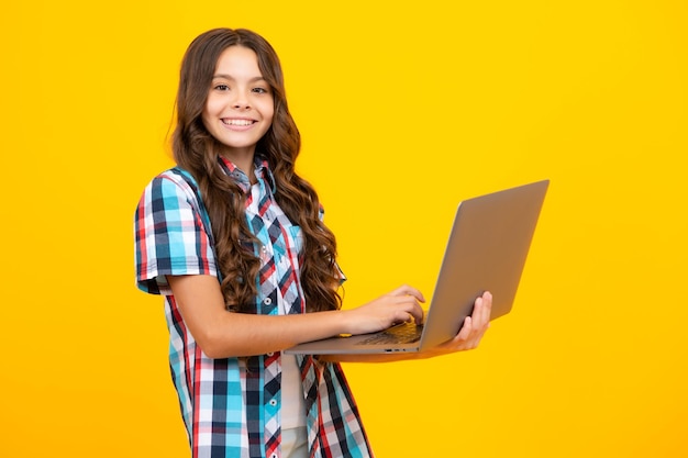 Młoda dziewczyna student trzymać komputer Zabawna uczeń z laptopem samodzielnie na żółtym tle Powrót do szkoły