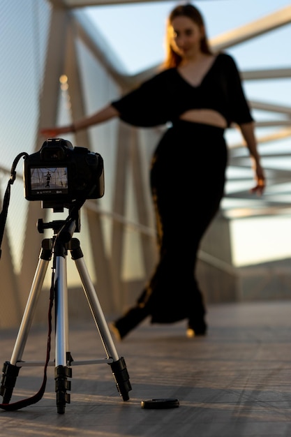 Młoda dziewczyna tańczy na kładce dla pieszych i filmuje się profesjonalną kamerą