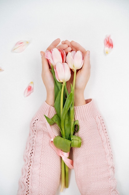 Młoda dziewczyna trzyma bukiet różowych tulipanów. Widok z góry, białe tło, miejsce na kopię tekstu.