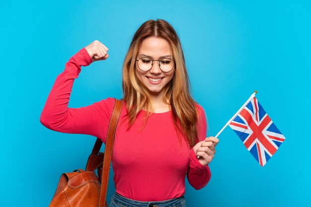 Młoda dziewczyna trzyma flagę Zjednoczonego Królestwa na odosobnionym niebieskim tle robi silny gest