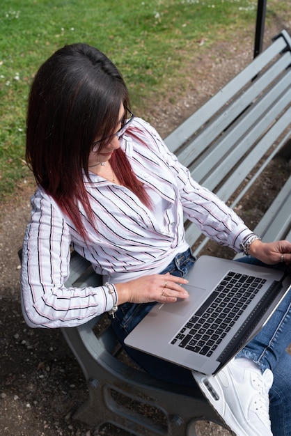 Młoda Dziewczyna Trzyma Koszulę I Patrzy Na Laptopa W Parku