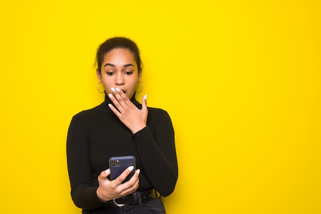 Zdjęcie młoda dziewczyna trzyma telefon, chętnie otrzyma powiadomienie. zdjęcie dziewczyny z ameryki łacińskiej nosi strój casual. koncepcja emocji i miłych uczuć.