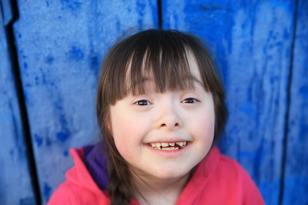 Młoda dziewczyna uśmiechając się na tle niebieskiej ściany.