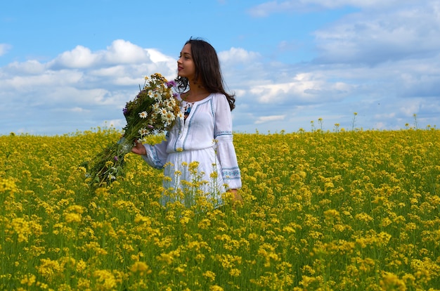 Młoda dziewczyna w białej sukni w polu kwiatów. Letnie pola z kwiatami na polu