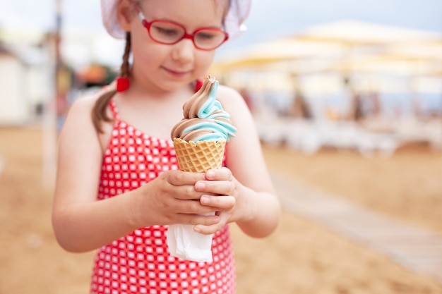 Młoda Dziewczyna W Czerwonym Kostiumie Kąpielowym Je Niebieskie Lody W Rogu Na Plaży