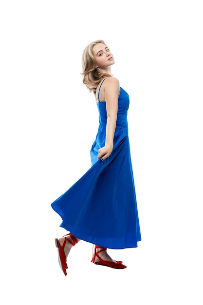 Młoda dziewczyna w długiej niebieskiej sukience Aktywność wdzięk i ruch Pełny wzrost Na białym tle Pionowo