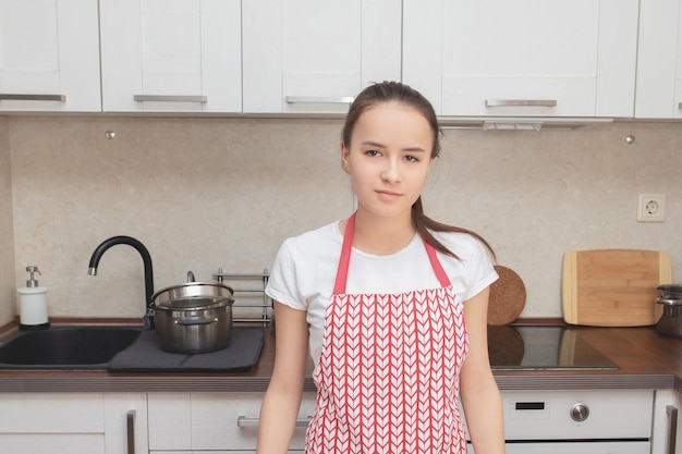 Młoda dziewczyna w fartuchu do gotowania w kuchni