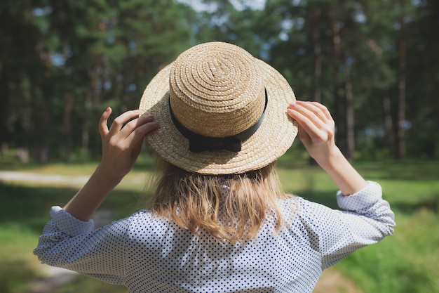młoda dziewczyna w słomkowym kapeluszu stojącym w lesie