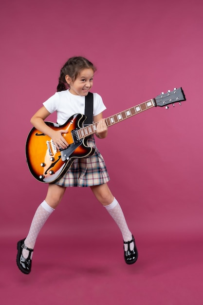 Młoda dziewczyna w szkolnym mundurku gra na gitarze elektrycznej