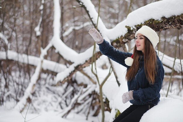 Młoda dziewczyna w winter park na spacerze. Święta Bożego Narodzenia w zimowym lesie. Dziewczyna cieszy się zimą w parku.