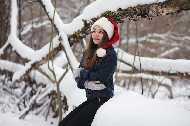 Młoda dziewczyna w winter park na spacerze. Święta Bożego Narodzenia w zimowym lesie. Dziewczyna cieszy się zimą w parku.