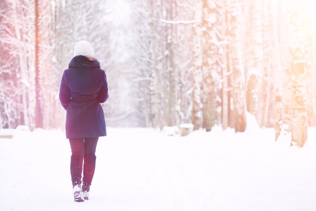 Młoda dziewczyna w winter park na spacerze. Święta Bożego Narodzenia w zimowym lesie. Dziewczyna cieszy się zimą w parku.