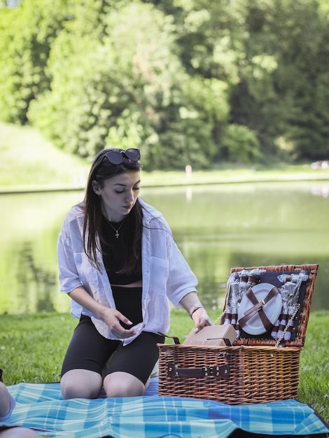 Młoda dziewczyna wyjmuje naczynia z kosza w parku
