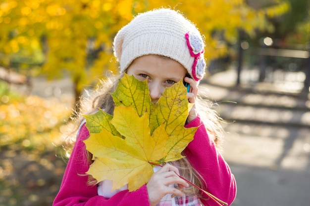 Młoda dziewczyna z jesień liśćmi klonowymi w ręce.