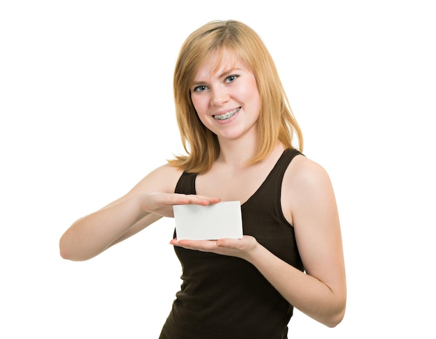 Młoda dziewczyna z nawiasami trzyma biały czysty papier na białym tle