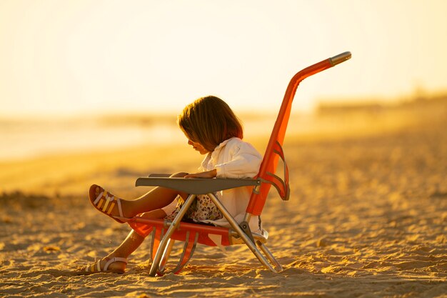 młoda dziewczyna z sandałami na plaży o zachodzie słońca