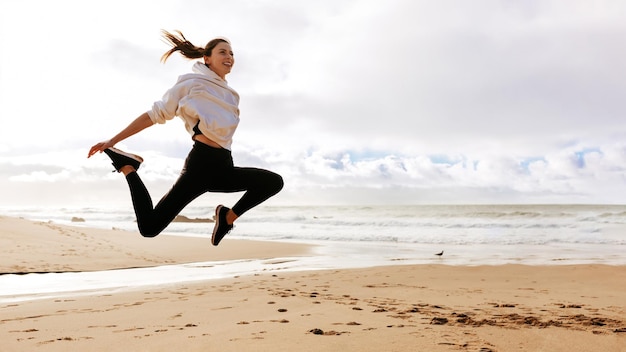Młoda fit dama skacząca wysoko na oceanie plażowym aktywna europejska kobieta pracująca na zewnątrz panorama z miejsca na kopię