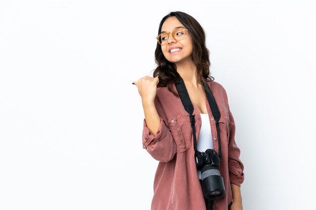 Młoda fotograf kobieta nad odosobnionym białym tłem wskazuje strona przedstawiać produkt
