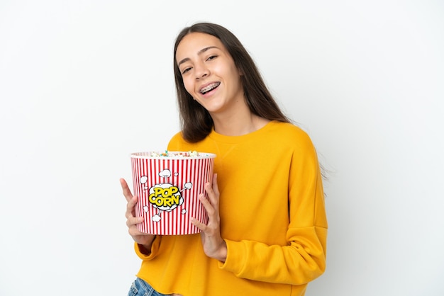 Młoda francuska dziewczyna na białym tle trzymająca duże wiadro popcornów