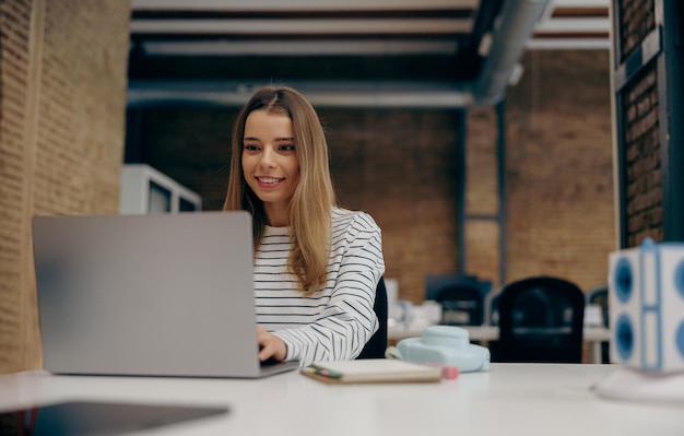 Młoda freelancerka pracuje na laptopie, siedząc w nowoczesnym coworkingu Koncepcja pracy na odległość
