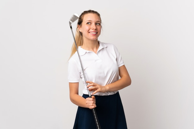 Młoda golfista kobieta śmia się nad odosobnionym biel ściany