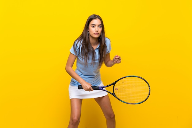 Zdjęcie młoda gracz w tenisa kobieta nad odosobnioną kolor żółty ścianą