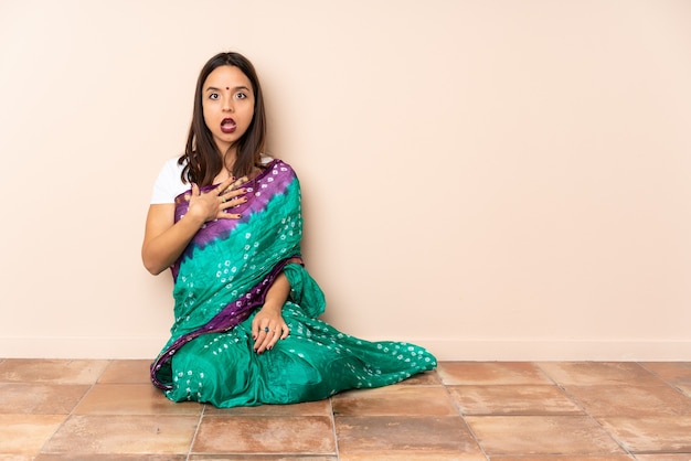 Młoda Hinduska siedząca na podłodze, zaskoczona i zszokowana, patrząc w prawo