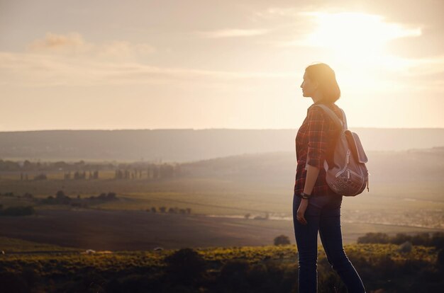 Młoda hipster dziewczyna cieszy się zachodem słońca na punkcie widokowym Podróżuje kobieta z plecakiem
