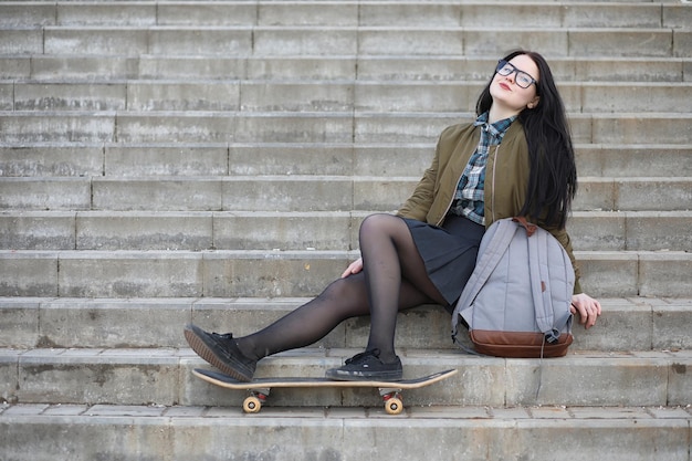 Młoda hipsterka jedzie na deskorolce Dziewczyny na spacer po mieście z deskorolką Wiosenne sporty na ulicy z deskorolką