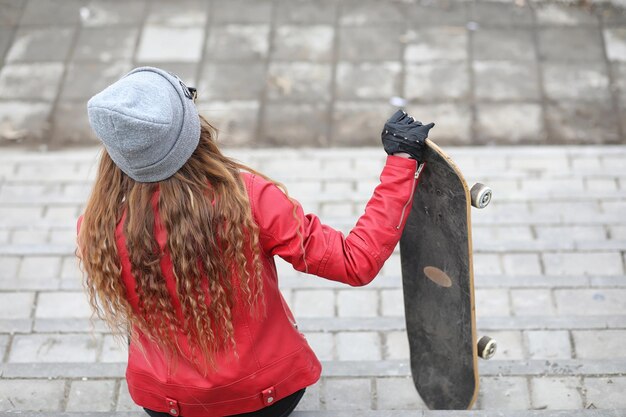 Młoda hipsterka jedzie na deskorolce Dziewczyny na spacer po mieście z deskorolką Wiosenne sporty na ulicy z deskorolkąxA