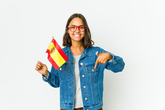 Młoda Hiszpanka trzyma flagę na białej ścianie wskazuje palcami w dół, pozytywne uczucie.