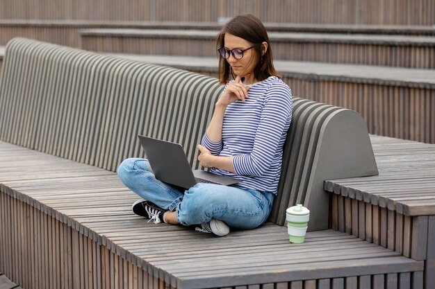 Młoda I Pewna Siebie Blogerka Lub Marketerka Pijąca Kawę I Pracująca Na Swoim Laptopie Pracuje W Krótkim Czasie