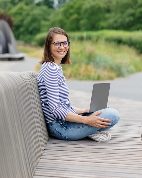 Młoda i pewna siebie kobieta, blogerka lub marketerka pijąca kawę i pracująca na swoim laptopie, pracuje w krótkim czasie