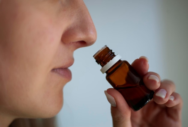 Młoda i piękna kaukaska kobieta wącha tubkę aromatycznego oleju, aby sprawdzić objawy Covid19 zapach objawy pandemii choroba zdrowie lekarstwo na chorobę Covid19 zapach Covid19 zapach nie zapach nos