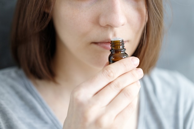 Młoda i piękna kobieta rasy kaukaskiej wąchająca tubkę aromatycznego olejku w celu sprawdzenia objawów Covid