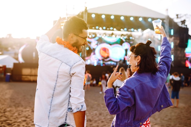 Młoda i wesoła para na festiwalu muzycznym Szczęśliwi przyjaciele piją piwo i dobrze się bawią