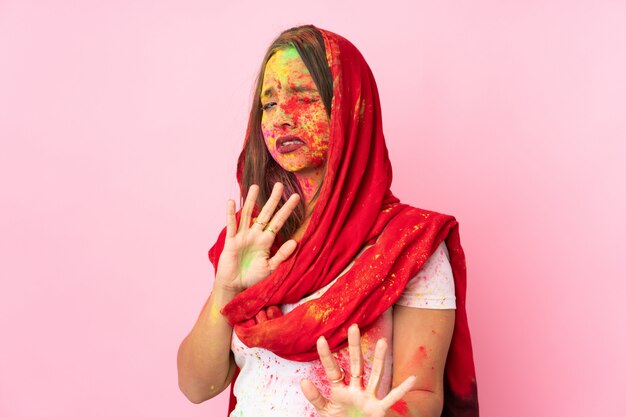 Młoda Indianka Z Kolorowymi Pudrami Holi Na Twarzy Na Różowej ścianie, Nerwowo Wyciągając Ręce Do Przodu