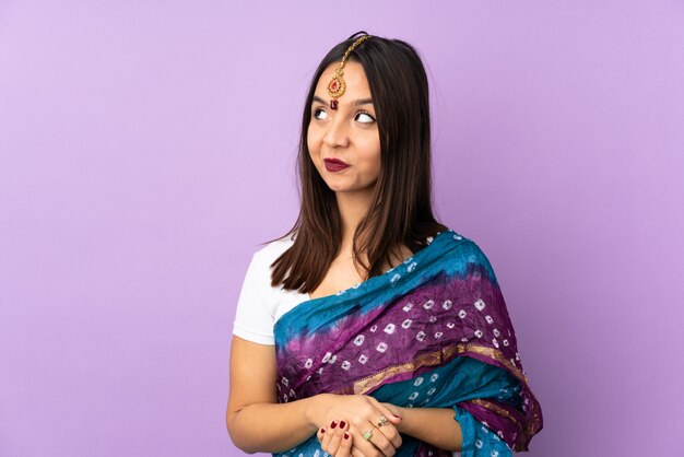 Młoda Indiańska kobieta odizolowywająca na purpurach ma wątpliwości podczas gdy przyglądający up