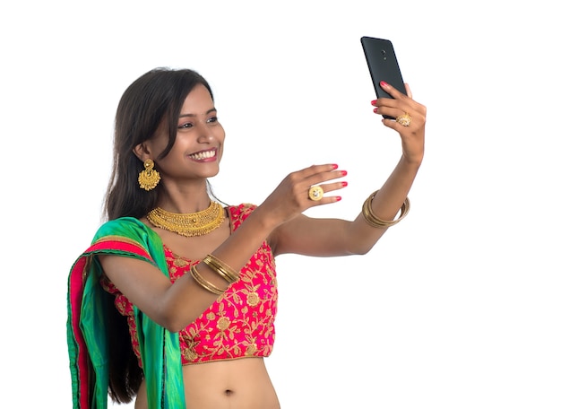 Młoda indyjska dziewczyna za pomocą telefonu komórkowego lub smartfona na białym tle