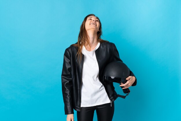 Młoda irlandzka kobieta trzymająca kask motocyklowy na białym tle ze śmiechu