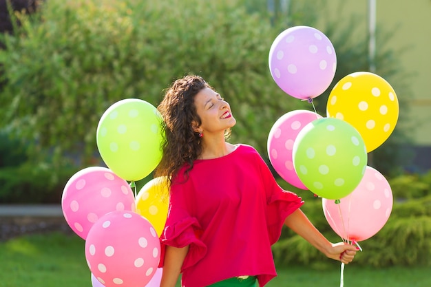 Młoda jaskrawa radosna brunetki dziewczyna z kolorowymi balonami. Szczęśliwy styl życia.