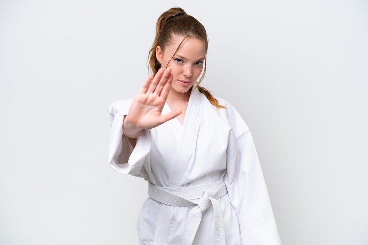 Zdjęcie młoda kaukaska dziewczyna robi karate na białym tle robiąc gest zatrzymania