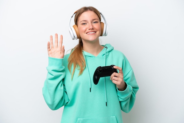 Młoda kaukaska kobieta grająca z kontrolerem gier wideo na białym tle salutująca ręką ze szczęśliwym wyrazem twarzy